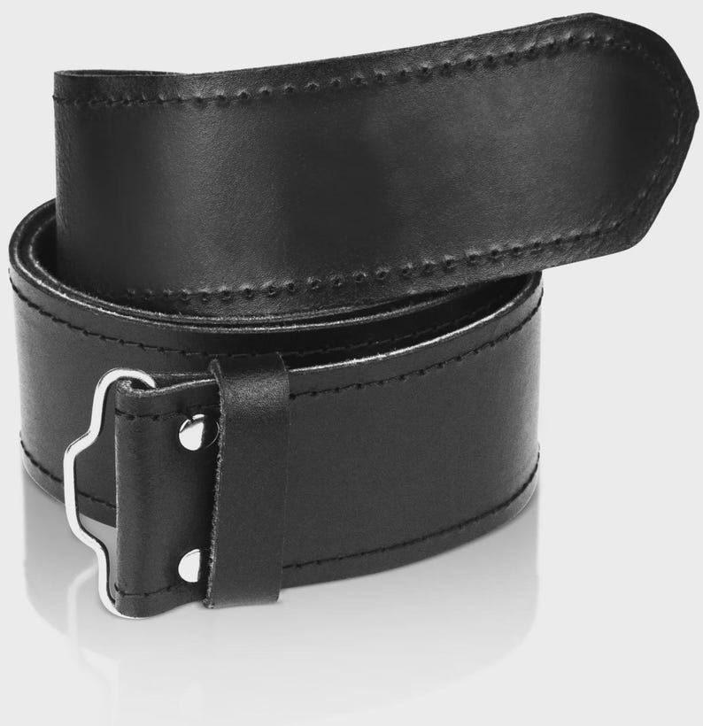 May include: A black leather belt with a silver buckle. The belt is folded in half and the buckle is visible in the center of the image.