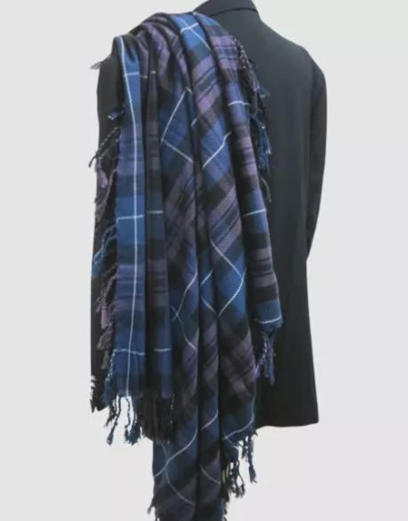 May include: A blue and purple plaid kilt with fringed edges draped over a black jacket.