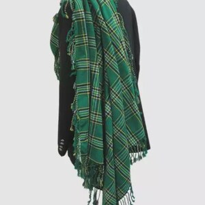 May include: A green and yellow plaid kilt with fringe. The kilt is draped over a black jacket.