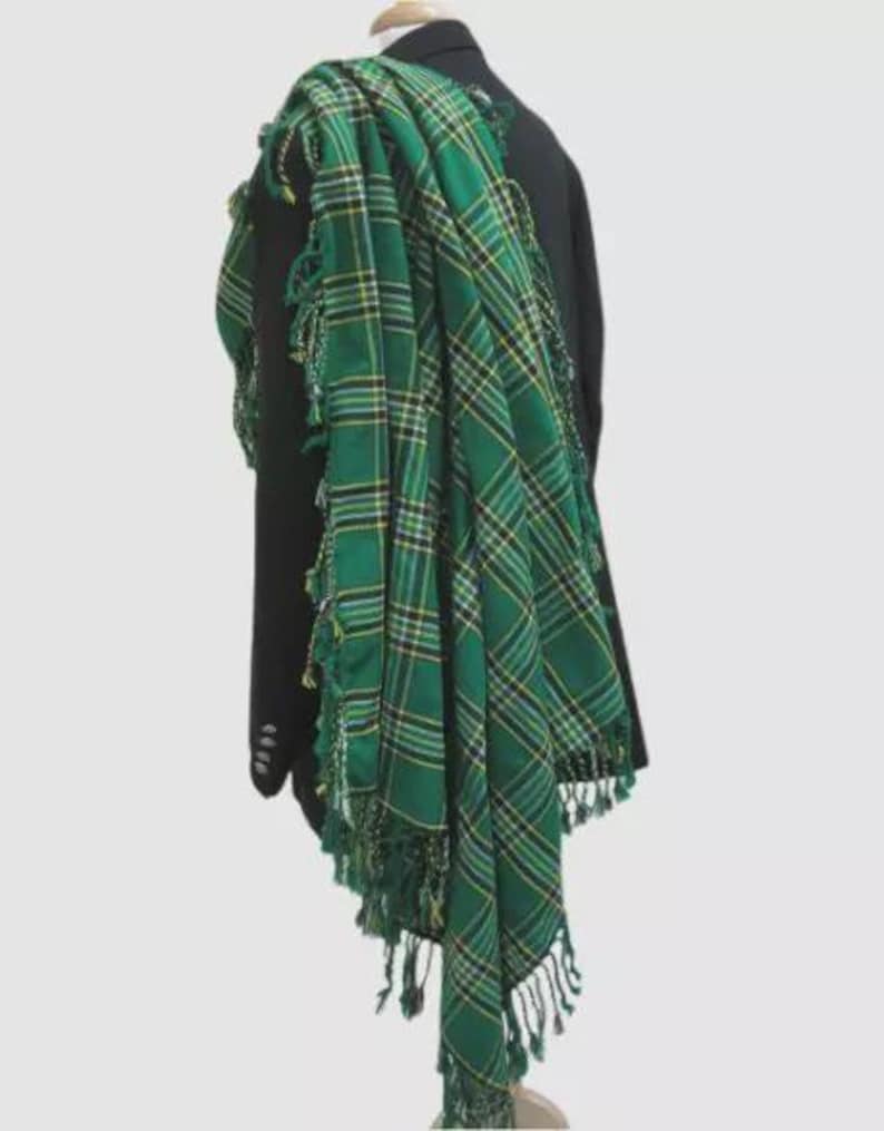 May include: A green and yellow plaid kilt with fringe. The kilt is draped over a black jacket.