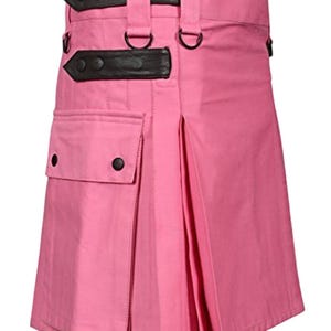 May include: A pink kilt with black leather straps and buckles. The kilt features a pocket on the front and pleats on the side. The kilt has two black leather straps with buckles and D-rings. The kilt is made of a sturdy fabric.