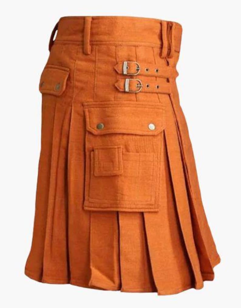 May include: Orange kilt with pleats, pockets, and buckle details. The kilt features a structured waistband with belt loops and two decorative buckles. The front has two pockets with button closures. This garment is a traditional style.