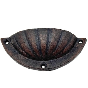 May include: A cast iron cabinet pull with a scalloped design in a dark brown and copper finish.