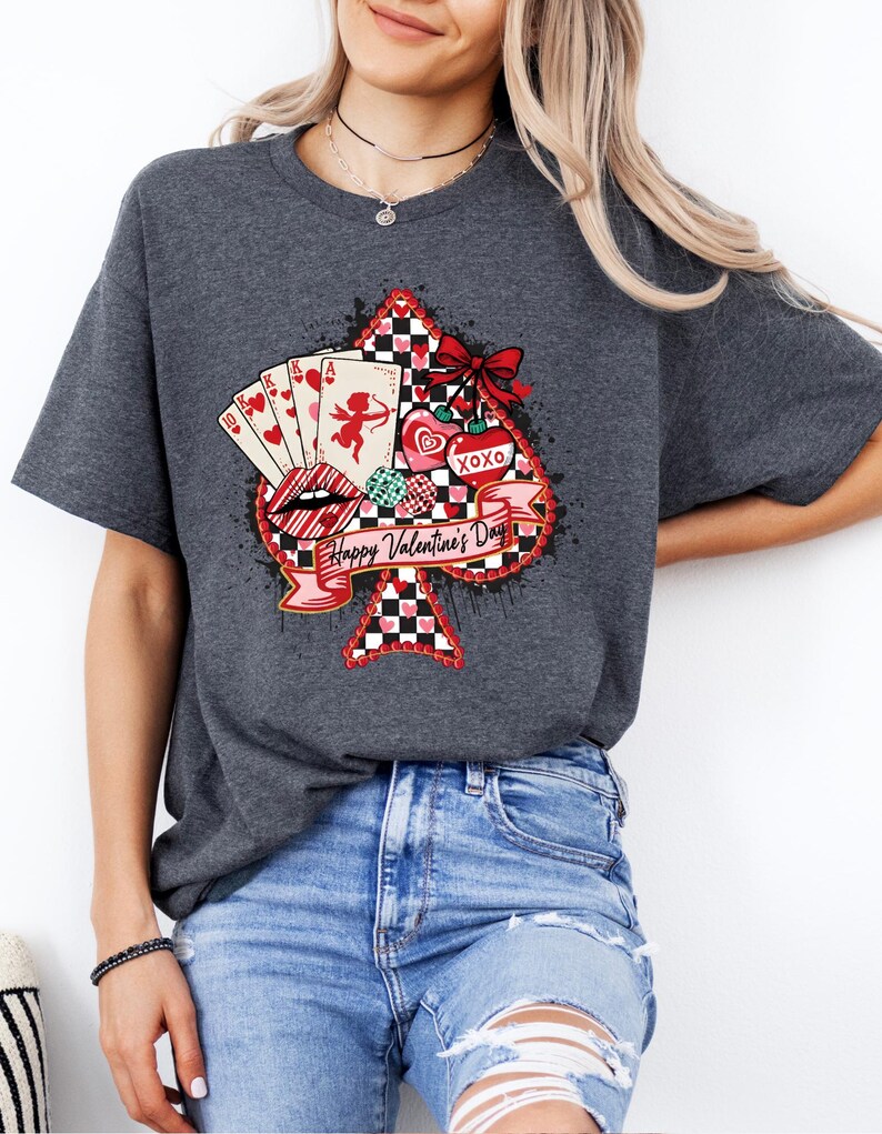 May include: Dark gray t-shirt featuring a Valentine's Day design. The graphic includes a spade shape with playing cards, lips, hearts, and the text "Happy Valentine's Day." The design incorporates red, black, and white elements.