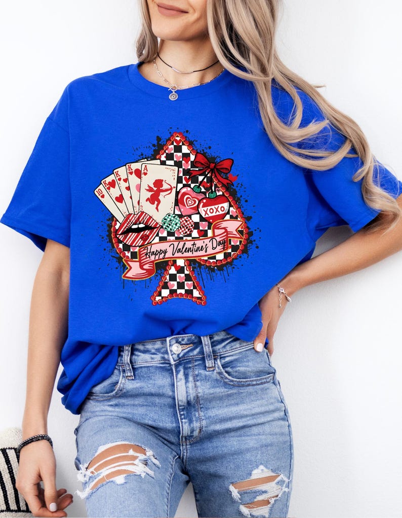 May include: Royal blue t-shirt featuring a Valentine's Day design. The graphic includes a spade shape with playing cards, a cupid, hearts, and the text "Happy Valentine's Day". A red bow and black and white checkered pattern complete the design.