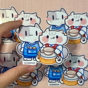 Pode incluir: Um conjunto de 10 adesivos coloridos com gatos de desenho animado fofinhos com diferentes expressões. Cada adesivo tem um fundo branco e apresenta um gato com uma atividade diferente, como pintar, assar ou tocar música. Os adesivos são perfeitos para adicionar um toque de fantasia a laptops, garrafas de água ou diários.