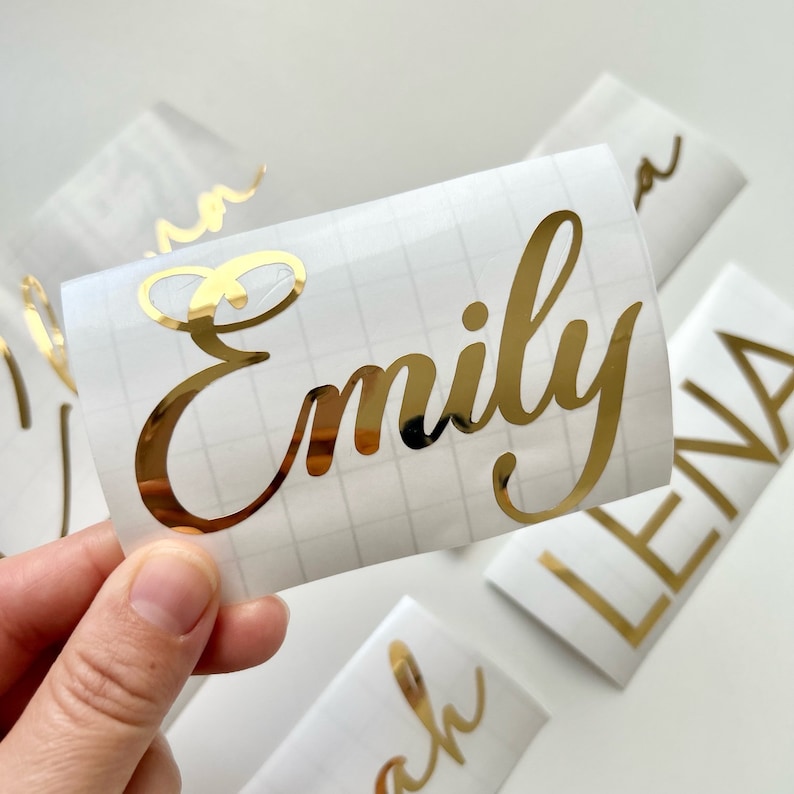 May include: Gold vinyl sticker with the name "Emily" written in a cursive font.