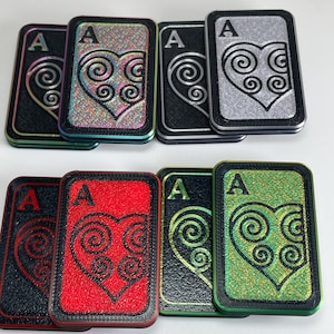 May include: Six playing cards with the Ace of Hearts. The cards are printed with a Celtic knot design in the shape of a heart. The cards are in different colors: black, red, green, silver, and iridescent.