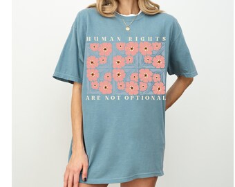 May include: A light blue t-shirt with a floral design and the text "HUMAN RIGHTS ARE NOT OPTIONAL".