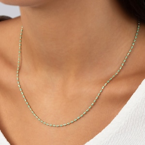 May include: A delicate gold chain necklace with small, light green beads. The necklace is simple and elegant, perfect for everyday wear.