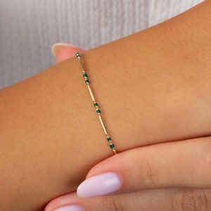 May include: A gold bracelet with small green beads and gold bars.