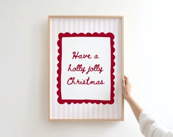 Może przedstawiać: Oprawiony wydruk z napisem "Have a holly jolly Christmas" w czerwonym skrypcie. Tekst znajduje się w białym prostokącie z czerwonym, falistym obramowaniem, na tle różowo-białych pasków. Rama jest jasnobrązowa.