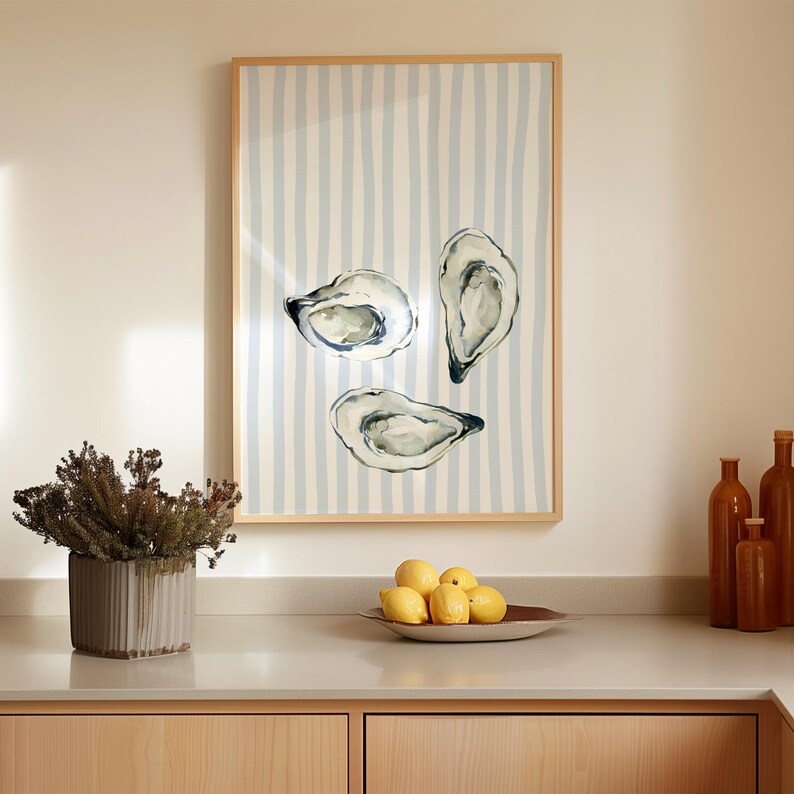 oyster print, coastal kitchen decor, watercolor seafood, preppy wall art, a watercolor painting of three oysters on the half shell, artfully arranged on a background of light blue and white vertical stripes, perfect for a beach house or kitchen.