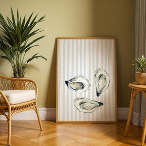 oyster print, coastal kitchen decor, watercolor seafood, preppy wall art, a watercolor painting of three oysters on the half shell, artfully arranged on a background of light blue and white vertical stripes, perfect for a beach house or kitchen.