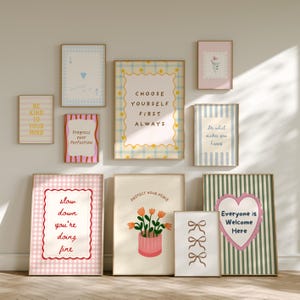 Puede incluir: Una colección de impresiones artísticas enmarcadas con citas inspiradoras e ilustraciones. Las impresiones presentan varios diseños, incluyendo motivos florales, corazones y texto como "Choose Yourself First Always" y "Everyone is Welcome Here."