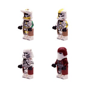 Può includere: Quattro minifigure Lego di personaggi di Star Wars. Le figure indossano armature bianche, gialle e rosse con dettagli neri. Le figure sono su una superficie bianca.