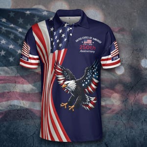 May include: A navy blue polo shirt featuring an American flag design and a soaring bald eagle. The shirt commemorates the 250th anniversary of the United States of America, with the years 1776 and 2026 displayed. The sleeves have American flag details.
