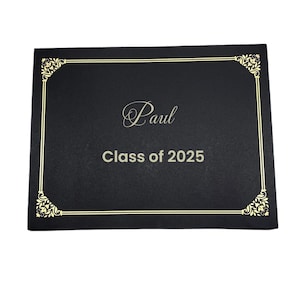 May include: A black diploma cover with gold trim and corner accents. The cover has the name "Paul" in elegant script and the text "Class of 2025" in a simple font. The overall design is formal and celebratory.