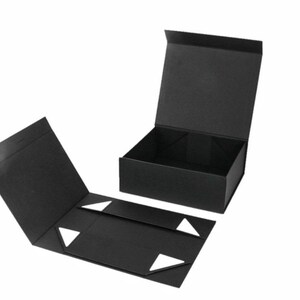 May include: Black folding gift box with a magnetic closure. The box is open, revealing the interior. The lid is open and the box is partially assembled. White triangular accents are visible on the inside flaps.