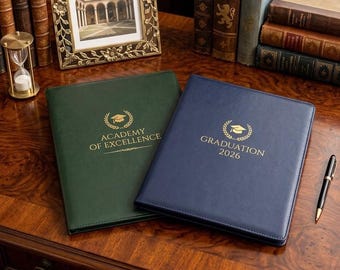 May include: A dark green folder with the gold text ACADEMY OF EXCELLENCE and a graduation cap icon, alongside a navy blue folder with the gold text GRADUATION 2026 and a graduation cap icon, both featuring stitched edges and a smooth finish.