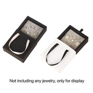 May include: Two jewelry display boxes, one black and one white, with open lids revealing gray interiors. Each box has a handle. The text at the bottom reads: "Not including any jewelry, only for display."