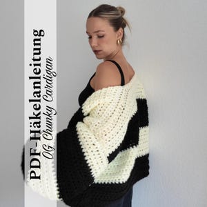 Könnte beinhalten: Ein grob gestrickter, übergroßer Cardigan in einem schwarz-cremefarbenen Colorblock-Design. Das dicke Strickstück hat ein auffälliges Muster und wird über einem schwarzen Top getragen. Das Bild enthält den Text "PDF-Häkelanleitung OG Chunky Cardigan."