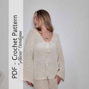 Könnte beinhalten: Cremefarbene Häkeljacke und passende Hose. Die Jacke hat einen V-Ausschnitt und einen Kordelverschluss. Der Text auf der linken Seite des Bildes lautet "PDF - Crochet Pattern 'Alicia' Cardigan."