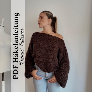 Könnte beinhalten: Ein dunkelbrauner Pullover mit freier Schulter. Der Pullover hat lange Ärmel und eine lockere Passform. Das Bild enthält auch den Text "PDF Häkelanleitung 'Emma' Pullover". Das Model trägt eine hellblaue Jeans.