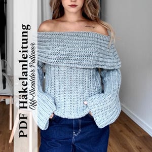 Könnte beinhalten: Ein hellblauer, offener Strickpullover mit langen Ärmeln. Der Pullover hat einen breiten, gefalteten Ausschnitt und eine Rippenstruktur.