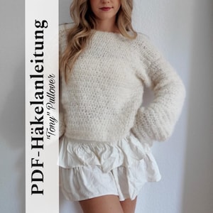 Könnte beinhalten: Cremefarbener, handgehäkelter Pullover mit langen Ärmeln. Der Pullover hat ein strukturiertes Stichmuster und einen runden Ausschnitt. Auch ein weißer Rüschenrock ist zu sehen. Der Text auf der linken Seite lautet "PDF-Häkelanleitung 'Tony' Pullover".