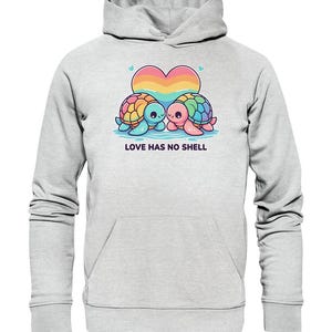 Könnte beinhalten: Ein hellgrauer Hoodie mit einem Regenbogenherz und zwei Comic-Schildkröten. Die Schildkröten schauen sich an und der Text "LOVE HAS NO SHELL" ist darunter gedruckt.