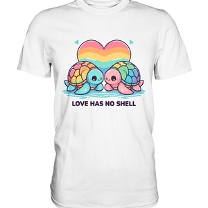 Könnte beinhalten: Weißes T-Shirt mit einer bunten Grafik von zwei Zeichentrickschildkröten mit Regenbogenpanzern, einem herzförmigen Sonnenuntergang und dem Text "LOVE HAS NO SHELL". Die Schildkröten befinden sich auf einem blauen, wasserähnlichen Hintergrund.