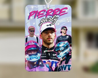 May include: Rectangular car air freshener featuring a portrait of Pierre Gasly with the text "Pierre Gasly" in pink and blue. The air freshener has a white string for hanging and includes images of Gasly in racing gear.