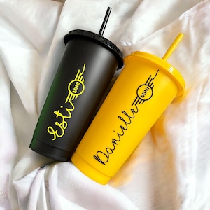 May include: Two personalised tumblers, one black and one yellow, with black lids and straws. Each tumbler features a yellow "MINI" logo and a name in a cursive font. The black tumbler has the name "Esti", and the yellow tumbler has the name "Danielle".