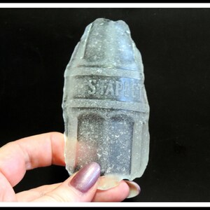 May include: A clear glass bottle with a textured surface and the word "STAPLES" embossed on the side.