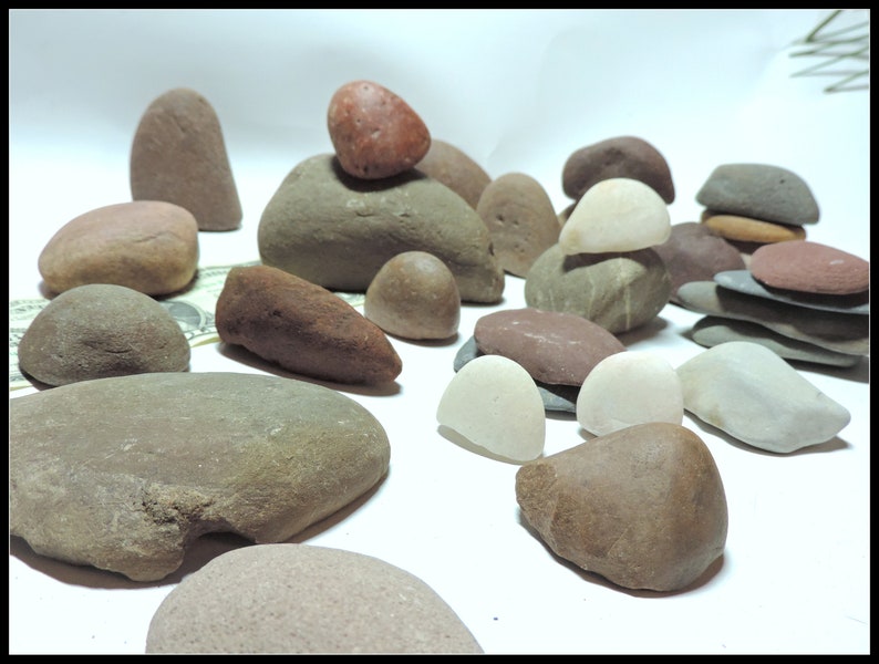 Pu&ograve; includere: Una collezione di pietre lisce e arrotondate in varie tonalit&agrave; di marrone, grigio e bianco. Alcune pietre sono impilate l'una sull'altra, creando piccole torri.