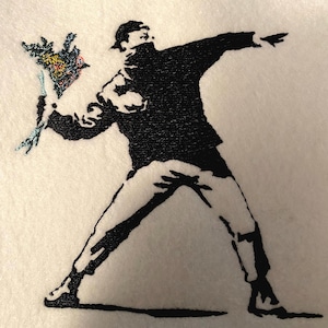 Puede incluir: Imagen bordada en blanco y negro de una persona lanzando un ramo de flores. La persona lleva gorra y bufanda. El ramo es colorido, con detalles azules, amarillos y rosas.