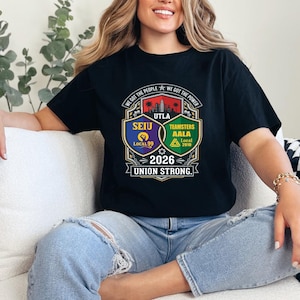 Op de afbeelding: Zwart T-shirt met een afbeelding met de tekst "WE GOT THE PEOPLE WE GOT THE POWER" en vakbondslogo's. Het ontwerp bevat de tekst "UTLA", "SEIU Local 99", "TEAMSTERS AALA Local 2010" en "2026 UNION STRONG."