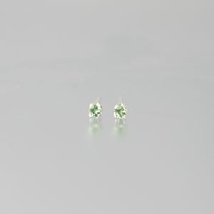 Könnte beinhalten: Ein Paar Ohrstecker mit runden, hellgrünen Edelsteinen. Die Ohrringe sind auf Silberstiften gefasst und haben ein schlichtes und elegantes Design. Die Edelsteine haben einen leichten Glanz und verleihen einen Hauch von Farbe.