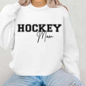 May include: White sweatshirt with black text that reads "HOCKEY Mom" in a varsity style font.