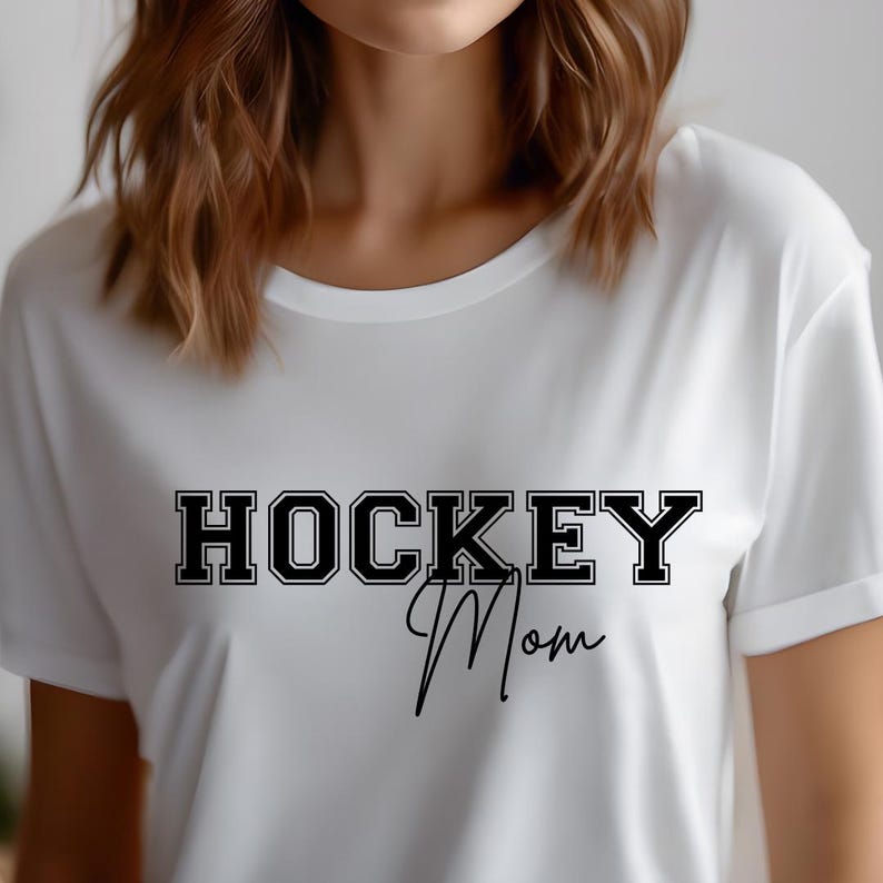 May include: White t-shirt with black text that reads "HOCKEY Mom" in a varsity style font.