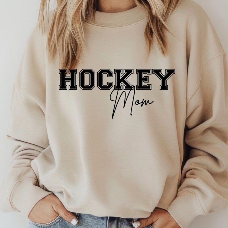 May include: A beige sweatshirt with the text "HOCKEY Mom" in black lettering.