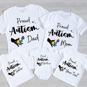 May include: Set of five white t-shirts with black text and a colorful puzzle piece design. The shirts say "Proud Autism" followed by "Dad", "Mom", "Sister", "Brother", and "Your Text".
