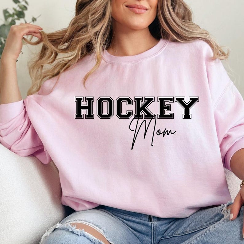 May include: A pink sweatshirt with the text "HOCKEY Mom" in black lettering.