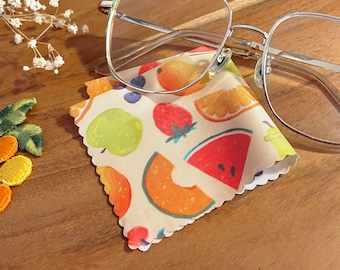 Puede incluir: Un paño de limpieza de microfibra blanco con un patrón de frutas coloridas. El paño presenta sandía, fresas, naranjas, peras y manzanas.