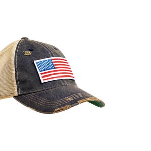 Op de afbeelding: Een blauwe denim trucker cap met een mesh achterkant en een distressed look. De cap heeft een klein Amerikaans vlag patch op de voorkant.