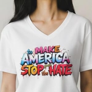 Puede incluir: Una camiseta blanca con cuello en V que presenta un gráfico multicolor estilo grafiti en el pecho. El texto "to MAKE AMERICA STOP the HATE" aparece en una mezcla vibrante de tonos azules, rosas, naranjas y rojos con efecto de pintura goteando.