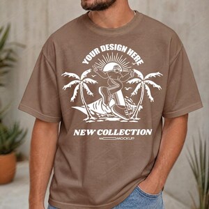 Peut inclure: T-shirt marron avec un motif blanc représentant un surfeur, des palmiers et le texte "YOUR DESIGN HERE" et "NEW COLLECTION". Le t-shirt a des manches courtes et un col rond.