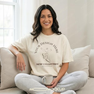 Peut inclure: Un t-shirt à manches courtes de couleur crème arborant un motif marron foncé représentant une personne qui marche, entouré du texte "YOUR DESIGN HERE" et "NEW COLLECTION" en cercle. Le t-shirt a un col rond et une coupe décontractée.