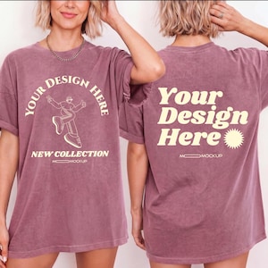 Puede incluir: Camiseta de color rosa polvoriento con el texto "YOUR DESIGN HERE" en un diseño circular, junto con un gráfico de una persona. La parte trasera de la camiseta también presenta el texto "Your Design Here". La camiseta es parte de una nueva colección.